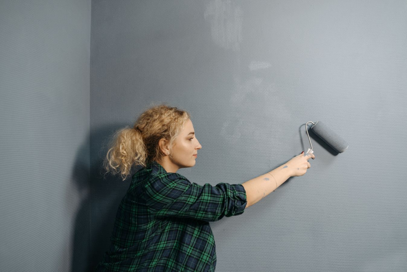 Malerin trägt mit der Rolle Farbe auf eine Wand auf